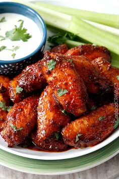 a white plate topped with wings covered in sauce and garnished with cilantro