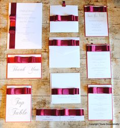 wedding stationery with red ribbon and matching envelopes on a wooden table in front of a thank you sign