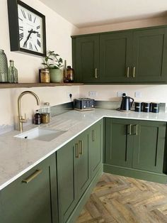 a kitchen with green cabinets and a white counter top that has a clock on the wall above it