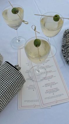 two martinis sitting on top of a table next to an empty purse and bag