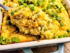 a casserole dish filled with green onions and topped with a spoon in it