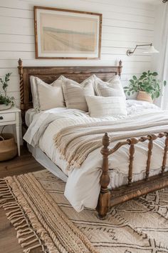 a bed with white linens and pillows in a bedroom next to a painting on the wall