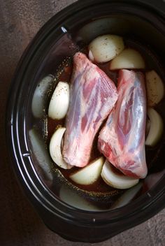 two pieces of meat and onions in a slow cooker