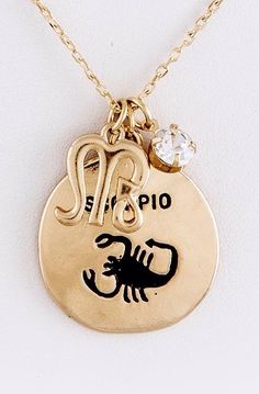 a gold plated necklace with a zodiac sign on it and a diamond in the middle