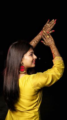 a woman in yellow dress holding her hands up with henna painted on the palm