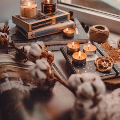 candles and books on a table near a window