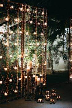 many lit candles are placed on the ground in front of a wall with latticed design