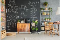 a chalkboard wall in the corner of a room next to a table and chairs