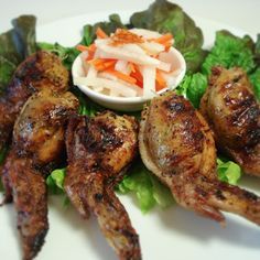 grilled chicken wings with lettuce and carrots on a white platter