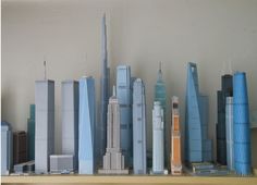 a group of tall buildings sitting on top of a wooden shelf