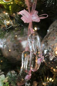 an ornament hanging from a christmas tree with pink ribbon and bows on it