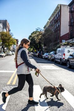 a woman walking her dog across the street