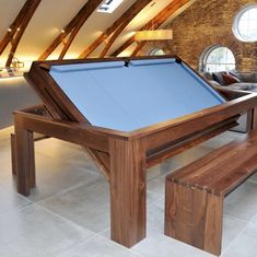 a pool table in the middle of a room with two stools and a bench