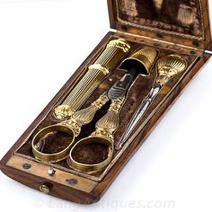 two pairs of scissors in a wooden box with gold trimmings on the handles