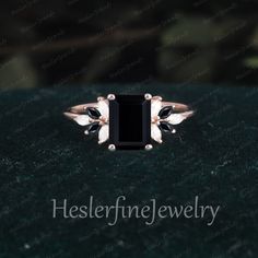 an engagement ring with black and white stones on it, sitting on a green surface