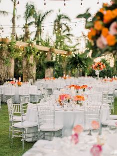 an outdoor wedding reception setup with white linens and pink flowers in tall vases