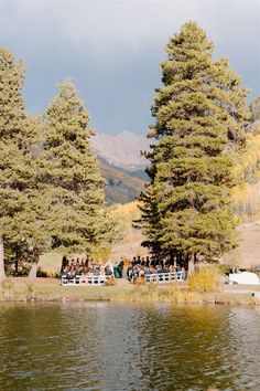 a group of people sitting at a table next to a lake