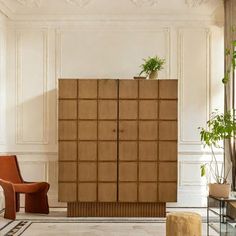 a living room filled with furniture and a tall wooden cabinet next to a planter