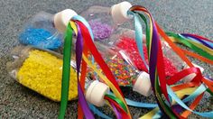 two plastic bottles filled with colorful beads and streamers on the floor next to each other