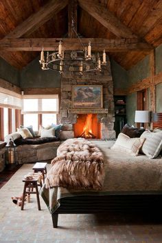 a large bedroom with a fireplace in the center and lots of pillows on the bed