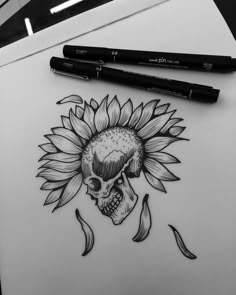 a drawing of a sunflower with a skull on it and two markers next to it