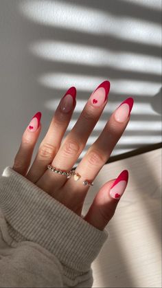 a woman's hand with red and pink nail polish on it, holding up her fingers