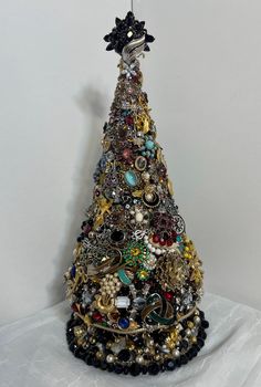 a small christmas tree made out of various types of jewelry and brooches on a white surface