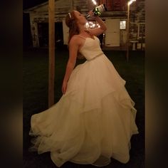 a woman in a wedding dress is drinking from a bottle with sparklers around her