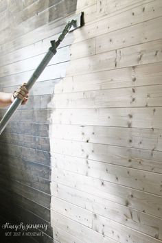 a man is using a water hose to clean the wood on a building's exterior