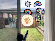 a little boy looking out the window at some kites hanging from it's side