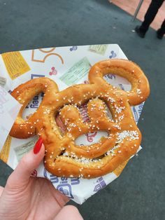 a person holding up a pretzel in front of the camera with sesame seeds on it