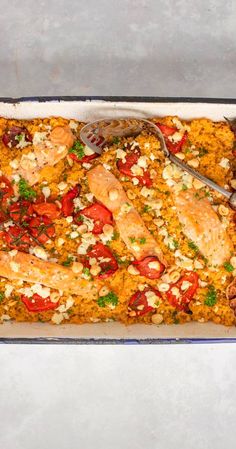 a casserole dish with chicken, tomatoes and other toppings on the side