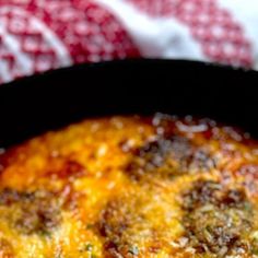 an omelet in a black pan on a red and white cloth