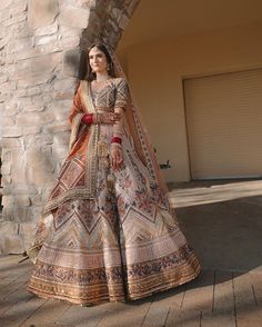 a woman standing in front of a brick wall wearing a bridal gown and veil