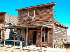 an old wooden building with antlers painted on it's front and side windows