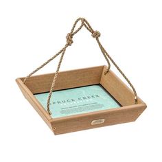 a small wooden box with rope hanging from it's sides and a book in the middle