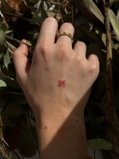 a person's hand with a small red tattoo on their left wrist and fingers