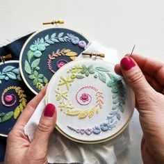 two hands are holding some embroiderys in front of each other