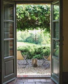 an open door leading to a patio with two lawn chairs and a table in the middle