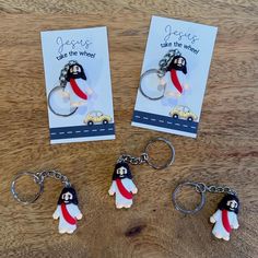 three keychains are shown on a table with two cards and one has a penguin holding a car