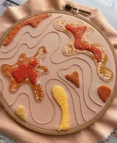 a hand embroidered starfish and seaweed design on a pink fabric with gold sequins