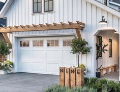 a white house with a wooden bench in front of it and plants on the outside