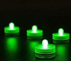 four green lights sitting on top of a black table next to each other in the dark