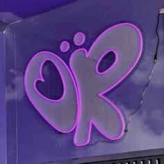 a neon sign with the letter o k on it in front of a purple wall