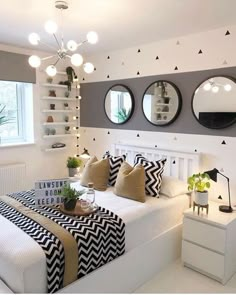 a bed room with a neatly made bed and three mirrors on the wall above it