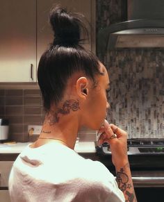 a woman with tattoos on her neck is looking at something in the distance while she brushes her teeth