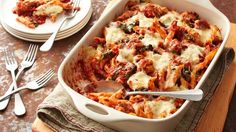 a casserole dish with meat, cheese and sauce in it on a wooden table