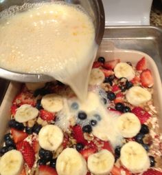 a pan filled with oatmeal, strawberries and blueberries being poured into it