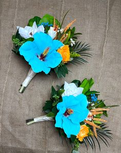 two bouquets of flowers are sitting on a bed sheet, one is blue and the other is yellow