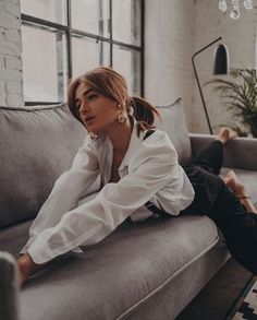 a woman sitting on top of a couch next to a window